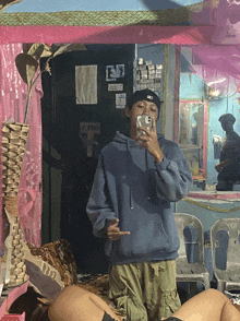 a man in a blue hoodie is taking a selfie in front of a door that says zero
