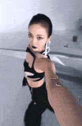 a woman in a black crop top and black pants is being held by a person .