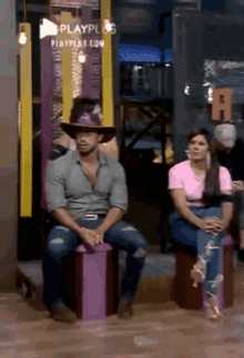 a man in a cowboy hat is sitting on a purple box next to a woman .