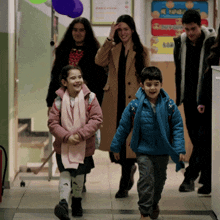 a group of people walking down a hallway with a sign on the wall that says children 's room