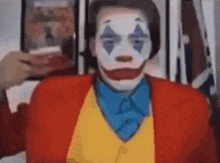 a man is wearing a clown costume and taking a selfie .