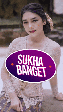 a woman sitting in front of a purple sticker that says sukha banget