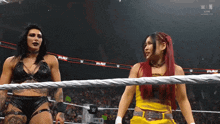 two women are standing in a wrestling ring and one is wearing a yellow outfit .