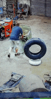 a man is working on a car in a garage with a tire in the foreground