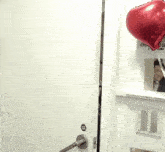 a red heart shaped balloon is hanging on a wall above a door