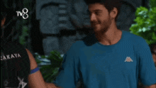 a man wearing a kappa t-shirt shakes hands with another man
