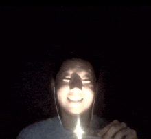 a man wearing ear buds is smiling with a light shining on his face