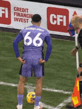 a soccer player with the number 66 on his jersey stands on the field