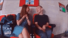 a man and a woman are sitting next to each other in a room with a sign that says planeta