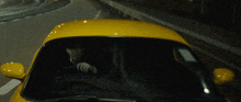 a man is driving a yellow car down a highway at night