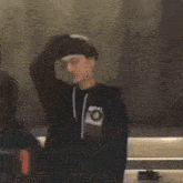 a young man wearing a black hoodie is standing next to another man .