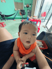 a baby is sitting on a person 's lap and holding a toy car