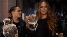 two women are holding wrestling championship belts in front of a screen that says usa live