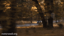 a white car is driving down a road with motorweek.org written in the corner
