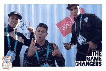 three young men pose for a photo in front of the olympic rings