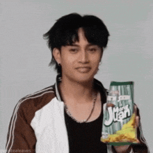 a young man is holding a bag of juan chips .