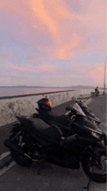 a black motorcycle is parked on the side of the road near the ocean .