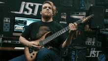 a man playing a guitar in front of a jst sign