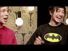 a man wearing a batman shirt is laughing with another man