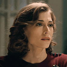 a woman with a serious look on her face is wearing a red shirt