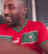 a man wearing a red and green puma jersey