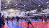 a group of people are playing volleyball in a gym with a sign on the wall that says ' volleyball '