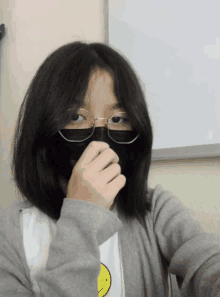 a girl wearing glasses and a mask covers her mouth