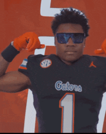 a man wearing sunglasses and a gators jersey is flexing his muscles