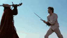 a man in a red cape is holding a sword in front of another man