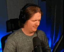 a man wearing headphones is sitting in front of a microphone and making a funny face .
