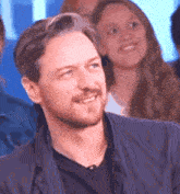 a man with a beard is smiling in a crowd of people .