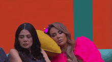 two women are sitting next to each other on a couch and talking to each other .