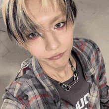 a close up of a person wearing a plaid shirt and a necklace that says ' uo ' on it