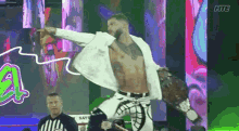 a man in a white suit is jumping in the air while holding a wrestling belt .