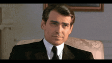 a man in a suit and tie is sitting on a chair