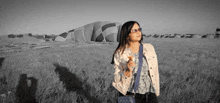 a woman stands in a field with a hot air balloon behind her