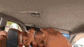 a woman is sitting in the back seat of a car while a man holds her hand .