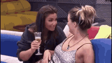 two women are sitting next to each other on a couch and one is holding a glass of champagne