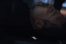 a man is laying on his back in a dark room with his eyes closed and his mouth open .