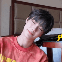 a young man in a red tie dye shirt is smiling with his eyes closed .