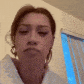 a woman wearing hoop earrings is making a funny face