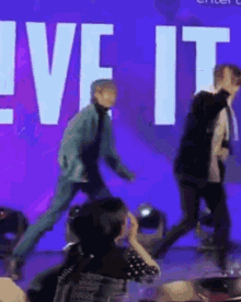 a group of people are dancing on a stage in front of a sign that says live it