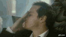 a man in a suit and tie is sitting in a chair holding his head .