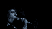 a close up of a person singing into a microphone in a dark room .