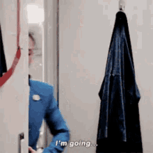 a woman in a blue suit and tie is standing in a doorway and talking .