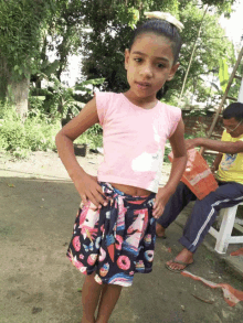 a little girl wearing a pink shirt and a skirt with ice cream and donuts on it