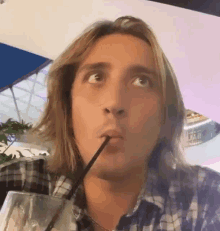 a man with long hair is drinking through a straw and looking up