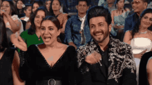 a man and woman are laughing in front of a crowd of people
