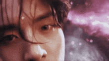 a close up of a person 's face with a pink background and a blurred background .