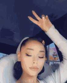 ariana grande is sitting in the back seat of a car with her hand in the air .